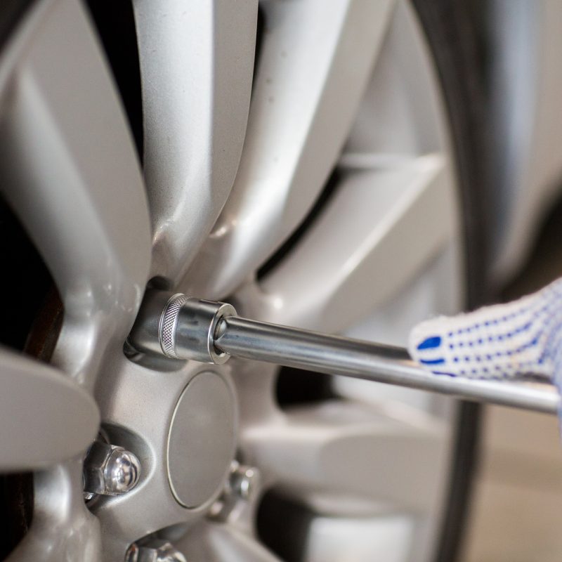 mechanic with screwdriver changing car tire