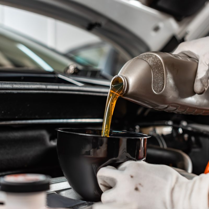 partial view of mechanic pouring motor oil at car engine